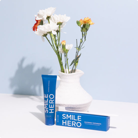 Smile Hero Whitening Toothpaste in front of a flower vase at home