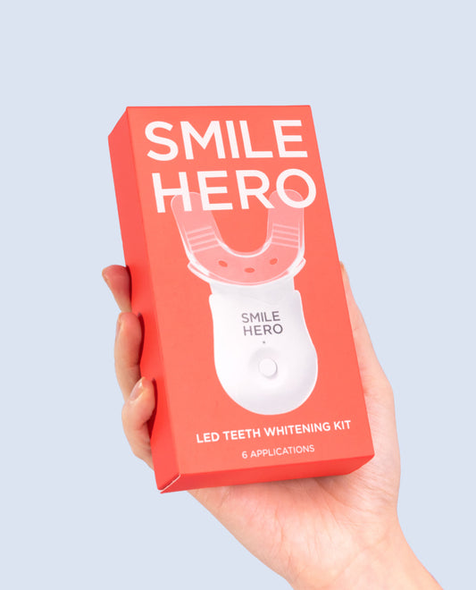 Smile Hero's LED Teeth Whitening Kit being held in a hand and about to be used at home