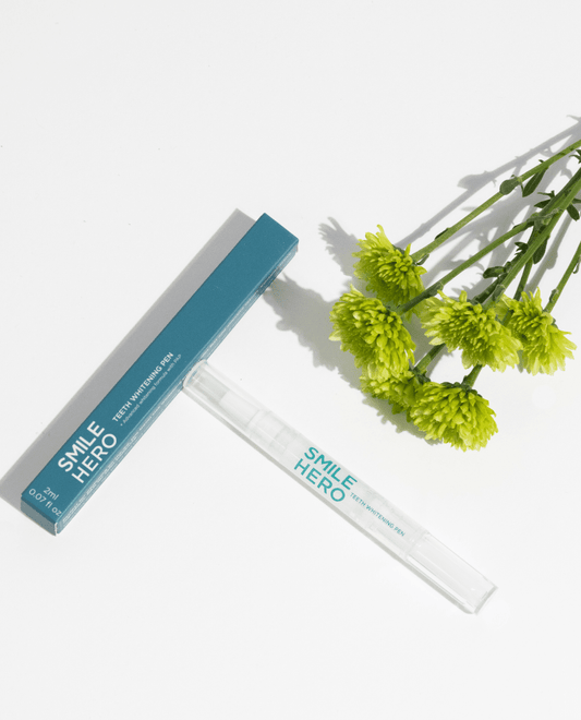 Smile Hero's Teeth Whitening Pen about to be used at home in front of natural ingredients like flowers